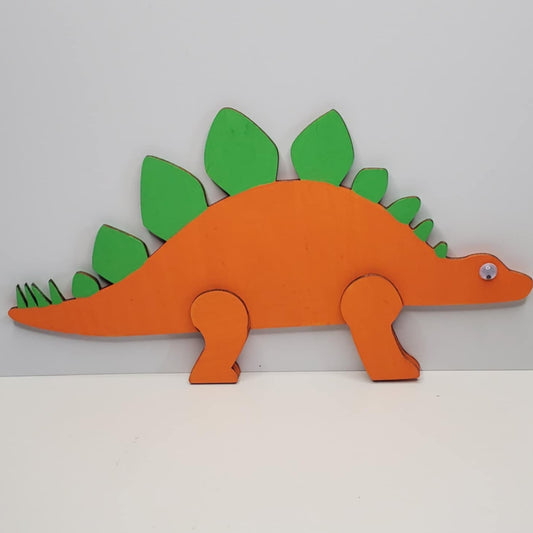 A laser cut wooden hand painted dinosaur decoration green and orange featuring wiggly eyes.