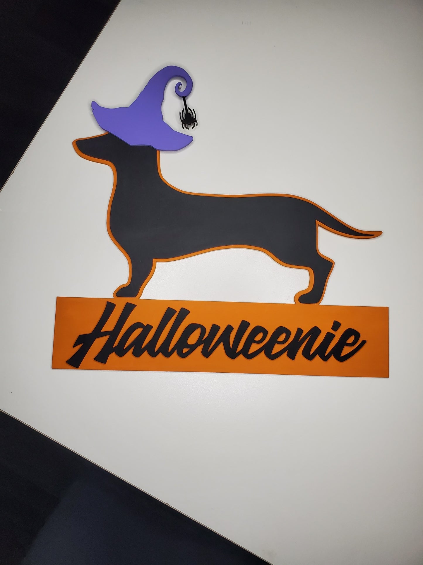 Halloween-themed dachshund silhouette with a purple witch hat and 'Halloweenie' text on an orange banner.