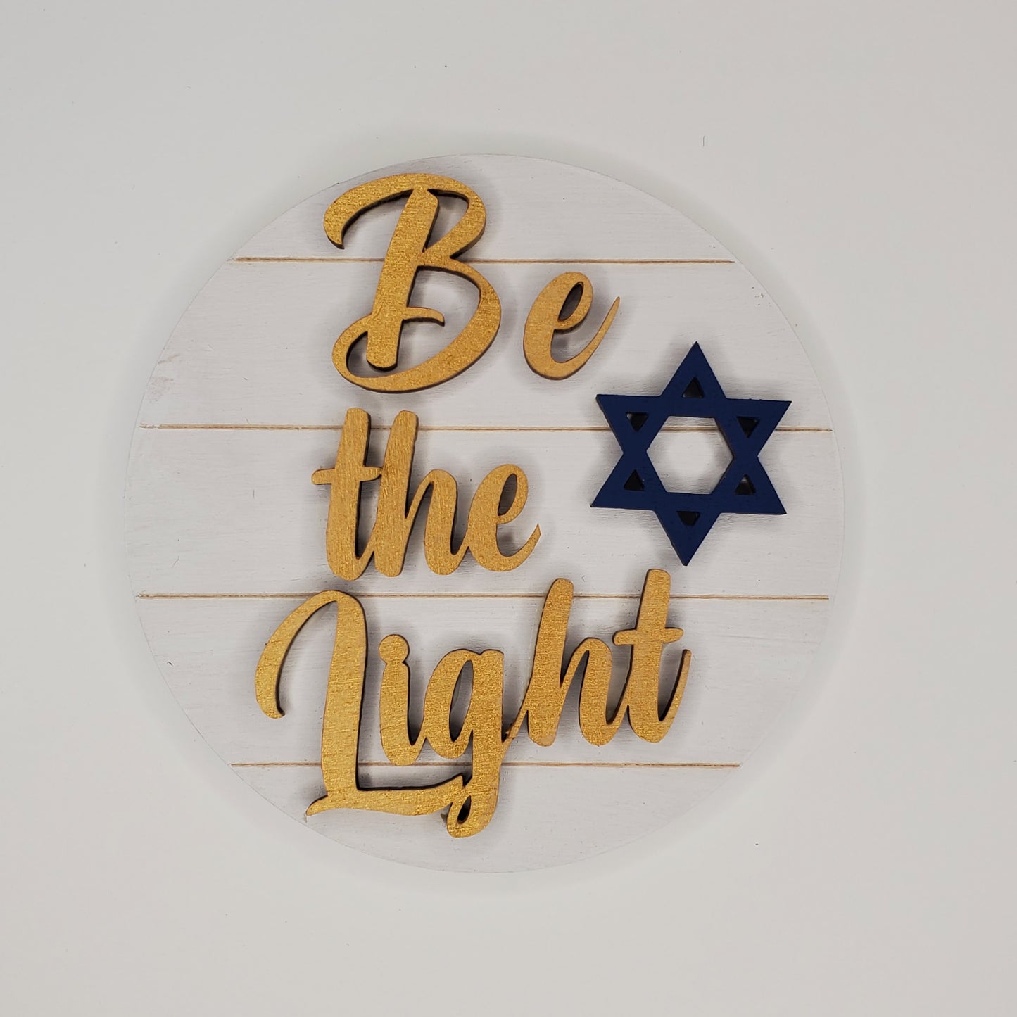 Words "Be The Light" On a White Wooden Background with a Star of David