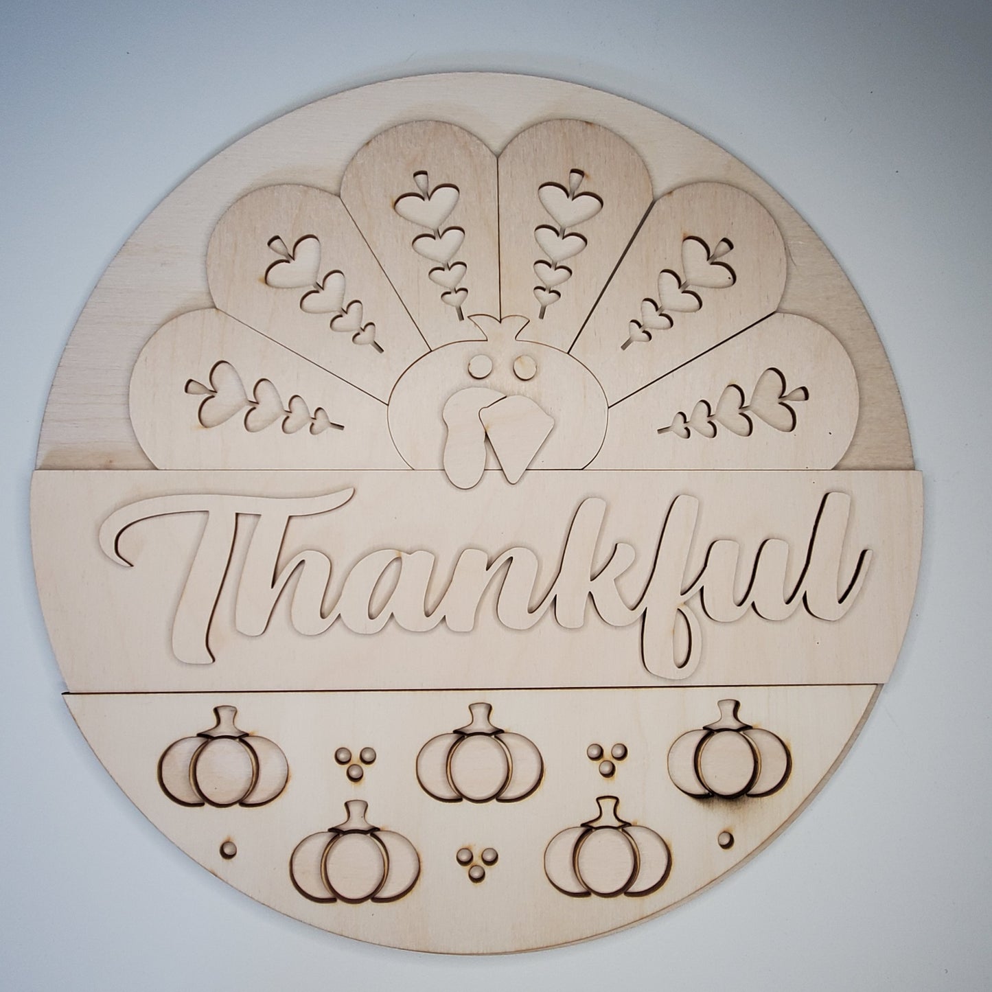 Wooden round decoration with 'Thankful' text and pumpkin designs