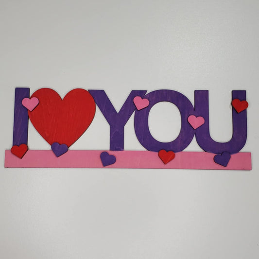 laser cut painted wood sign I love you with love being replaced by a heart. With clean, precise edges and added painted hearts to embellish.
