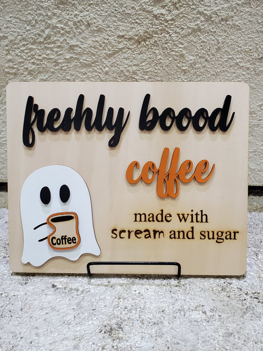 Decorative sign with ghost and coffee cup design on a wooden board
