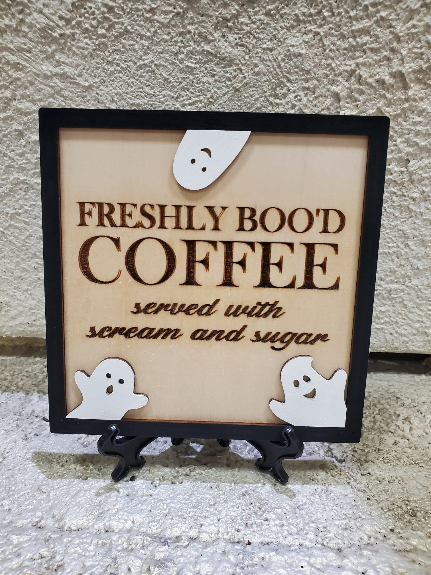 Decorative sign with 'Freshly Bood Coffee' text and ghost illustrations on a stand.