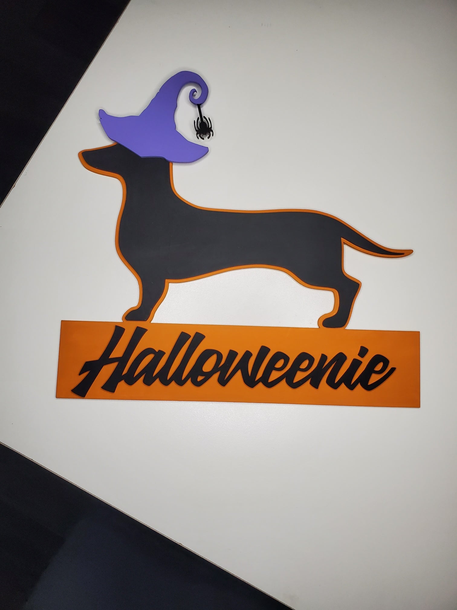 Halloween-themed dachshund silhouette with a purple witch hat and 'Halloweenie' text on an orange banner.