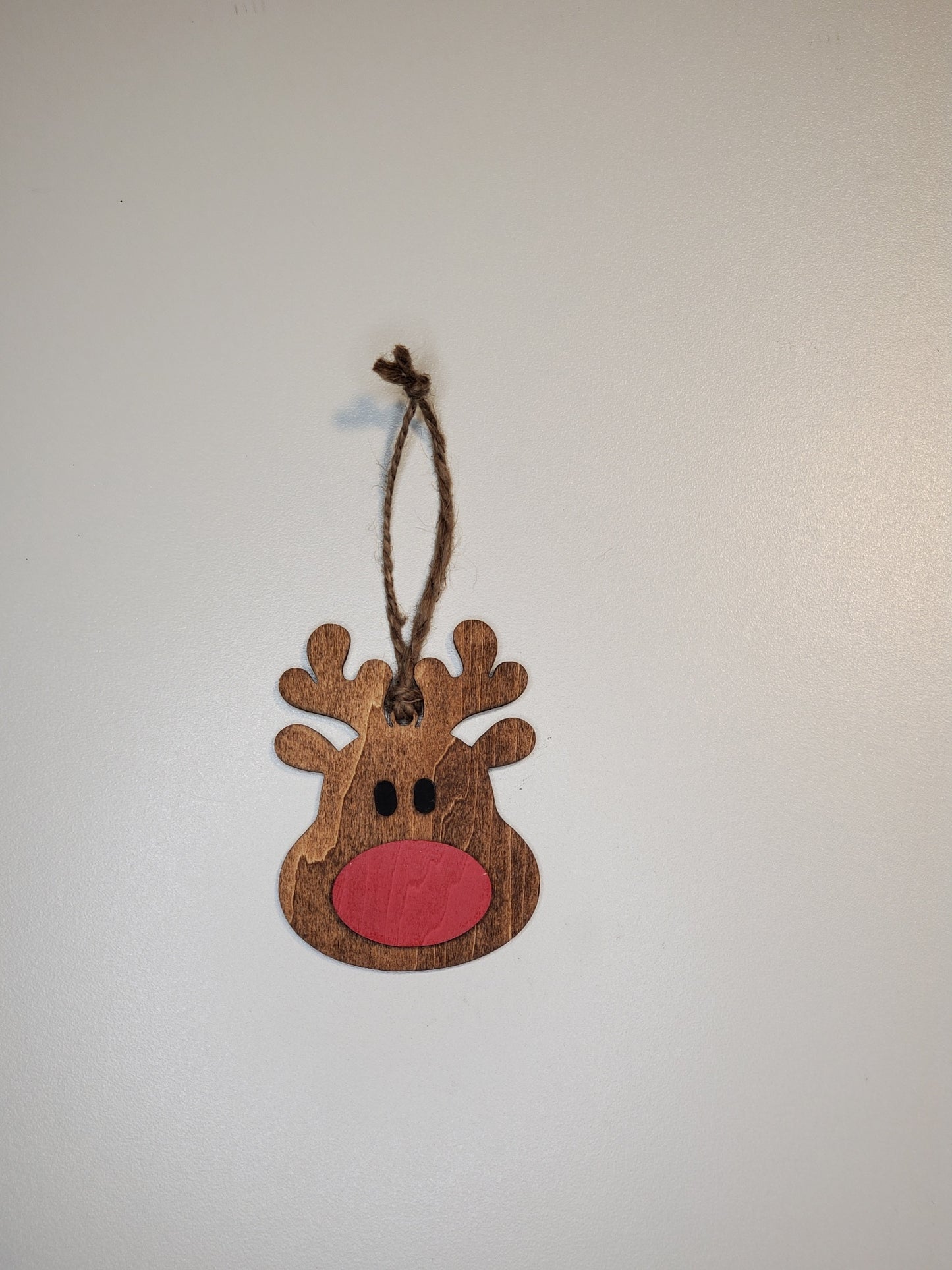 Wooden reindeer ornament with a red nose on a white background