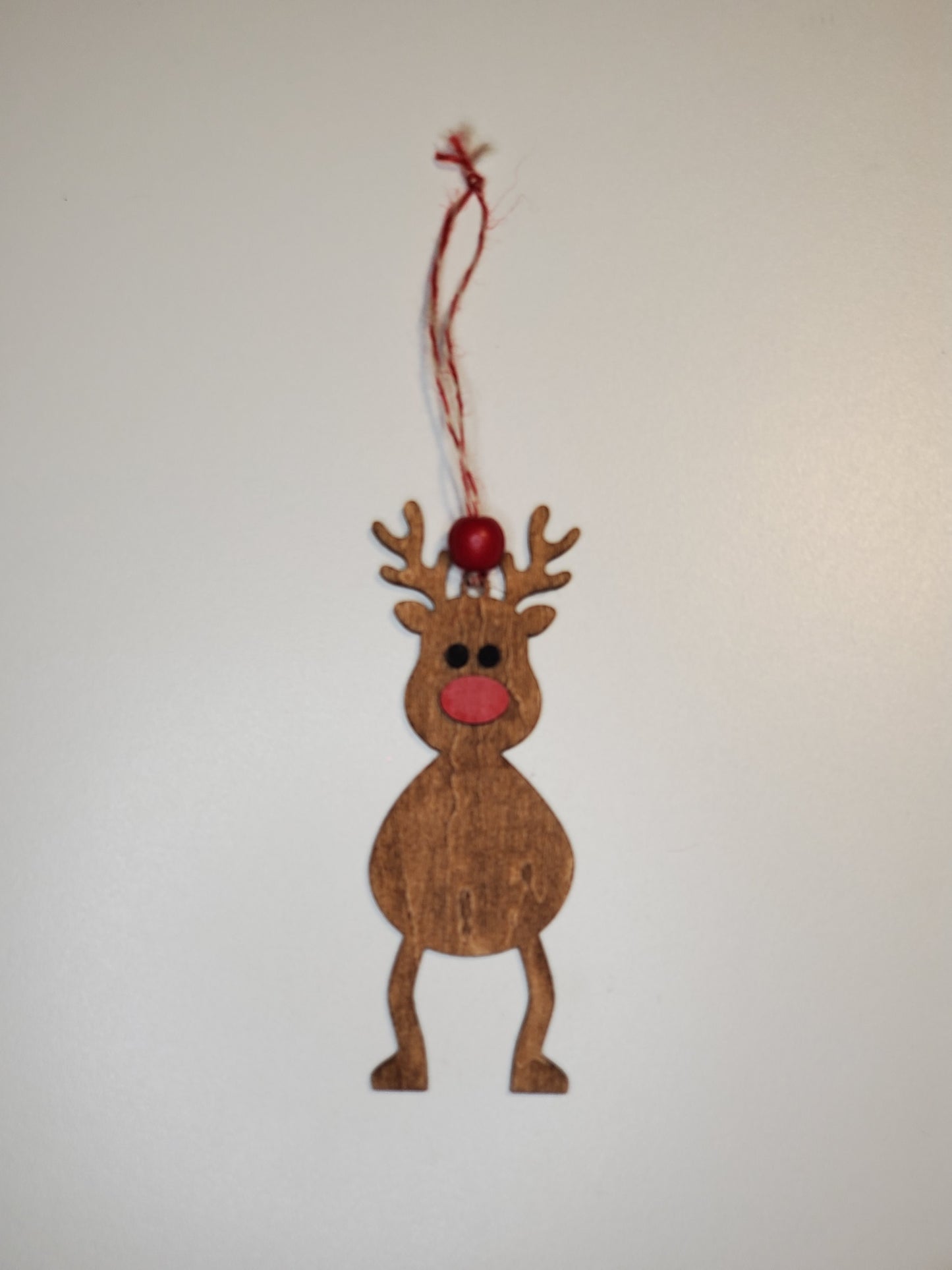 Wooden reindeer ornament with a red nose on a white background