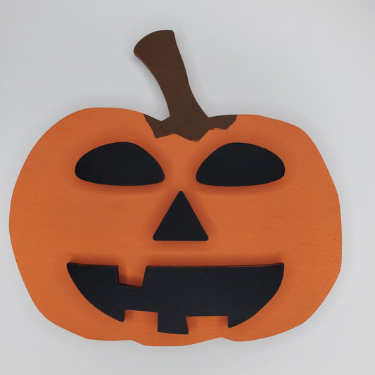 An orange pumpkin-shaped wooden cutout with a black jack-o'-lantern face and brown stem. Available in completed item or DIY kit. 