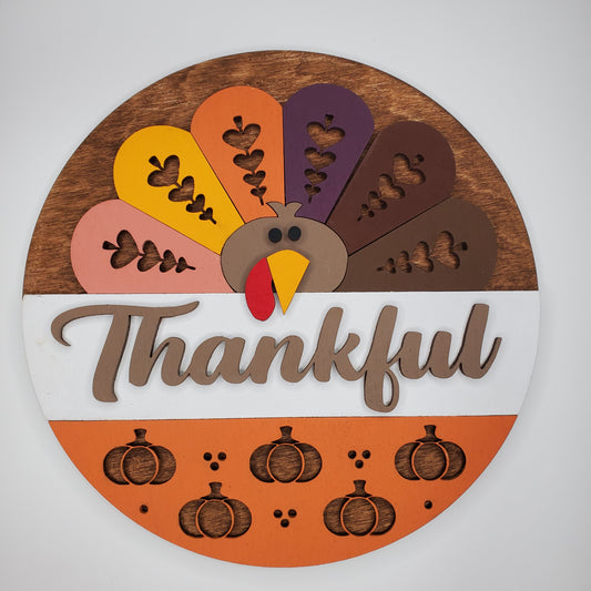Colorful Turkey Cutout on a Wooden Round With Text "Thankful" and Pumpkin Details