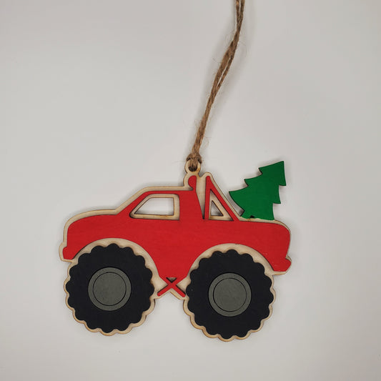 Decorative ornament shaped like a red monster truck with black wheels and a green tree on a white background