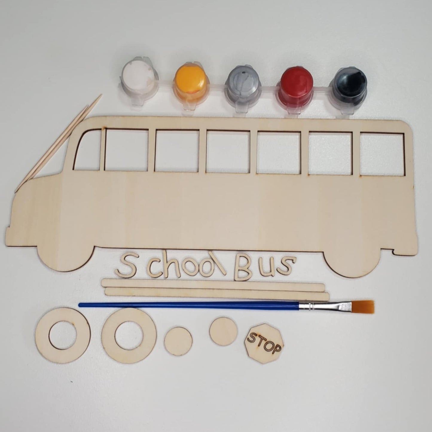 A laser cut wood school bus DIY kit with paint, paintbrush, glue and stand included to create yourself